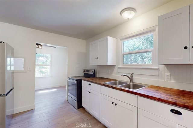 kitchen with white cabinetry, white refrigerator, sink, butcher block countertops, and stainless steel electric range