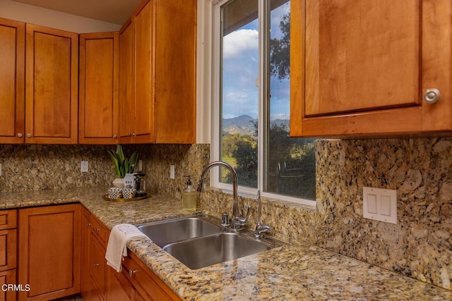 kitchen featuring tasteful backsplash, light stone countertops, sink, and a mountain view