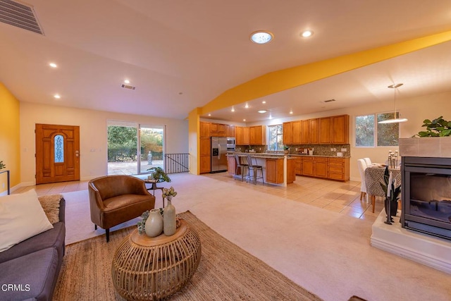 living room featuring light carpet, a healthy amount of sunlight, and vaulted ceiling