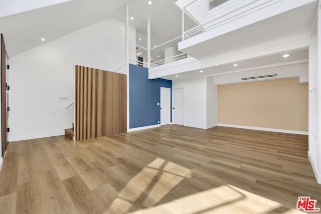 unfurnished living room with a towering ceiling and wood-type flooring