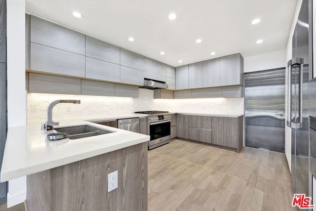 kitchen with kitchen peninsula, light hardwood / wood-style flooring, sink, extractor fan, and stainless steel range