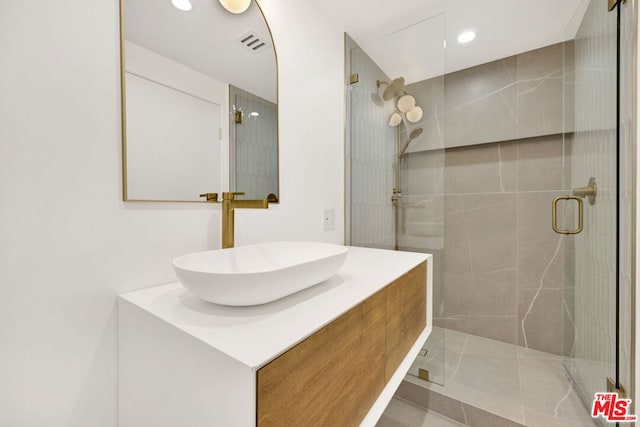 bathroom featuring tile patterned floors, a shower with door, and vanity