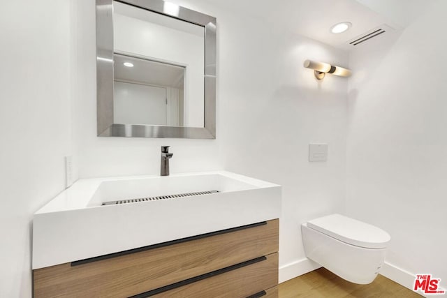 bathroom with hardwood / wood-style flooring, vanity, and toilet