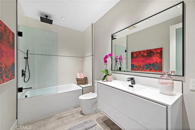 full bathroom with wood-type flooring, tiled shower / bath, vanity, and toilet