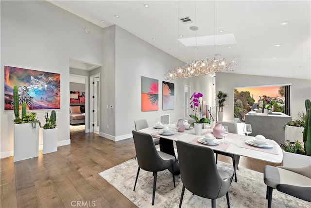 dining room with high vaulted ceiling and hardwood / wood-style flooring