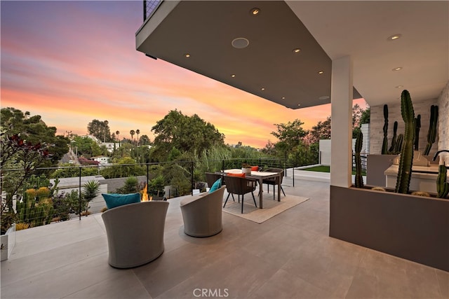 patio terrace at dusk featuring a balcony