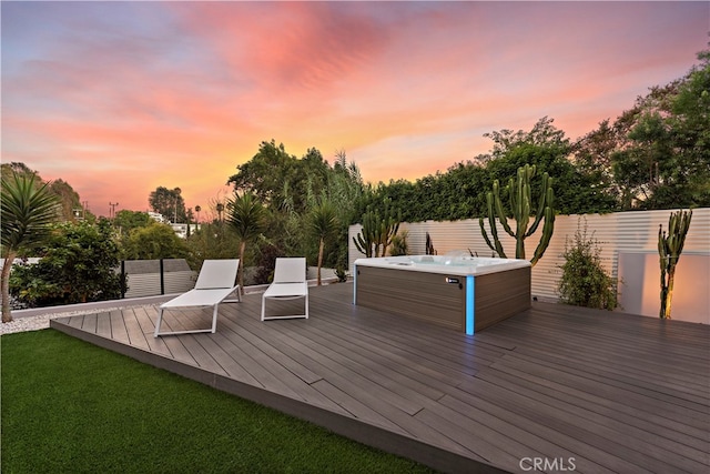 deck at dusk featuring a lawn