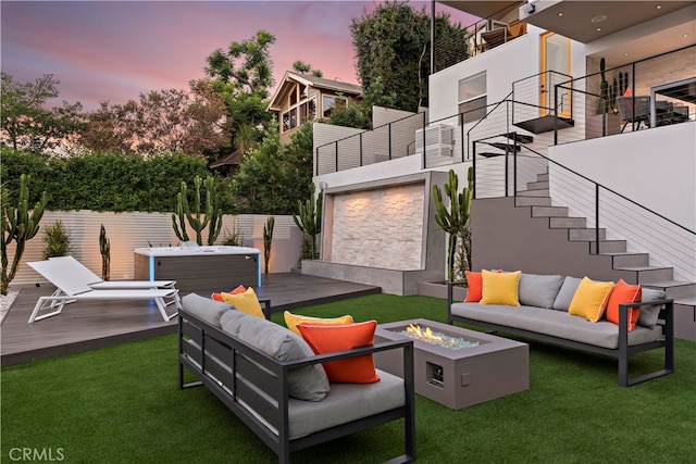 patio terrace at dusk featuring a hot tub, a deck, and an outdoor living space with a fire pit