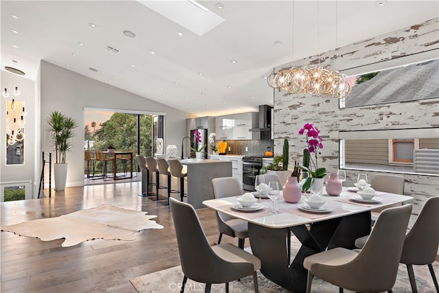 dining space with wood-type flooring and lofted ceiling with skylight