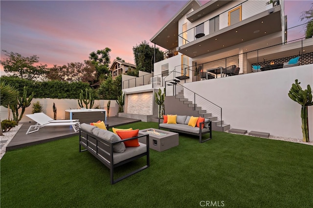 patio terrace at dusk featuring a lawn and an outdoor living space with a fire pit