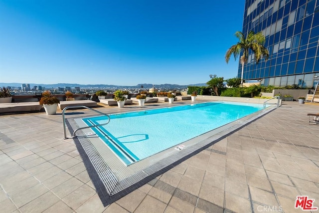 view of swimming pool featuring a patio and a mountain view