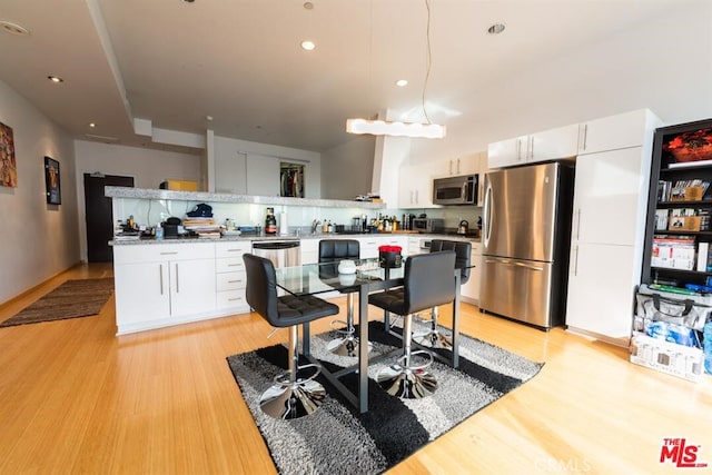 kitchen featuring stainless steel appliances, light hardwood / wood-style floors, and white cabinetry