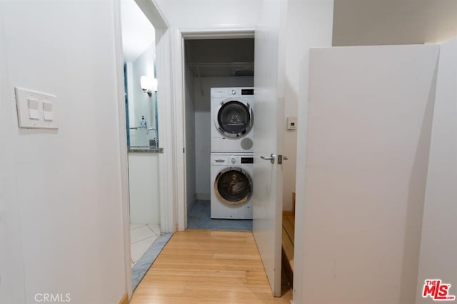 washroom with light wood-type flooring and stacked washer / drying machine