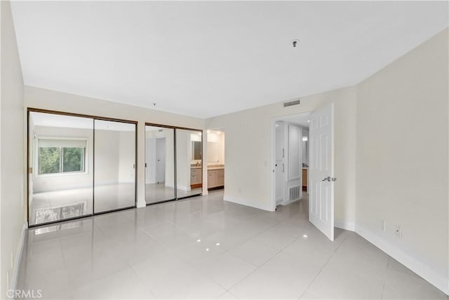260 Cagney Ln Unit 105, Newport Beach, CA 92663 - unfurnished bedroom with multiple closets, baseboards, and light tile patterned flooring