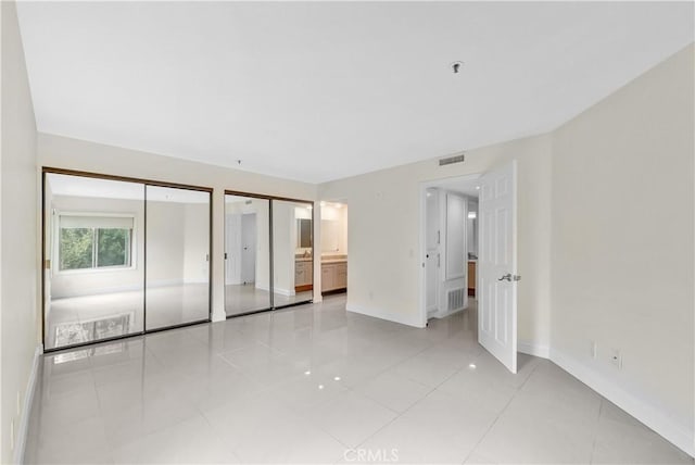 260 Cagney Ln Unit 105, Newport Beach, CA 92663 - unfurnished bedroom featuring two closets and light tile patterned flooring