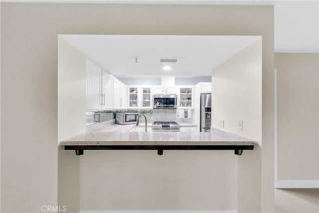 kitchen with a breakfast bar, kitchen peninsula, white cabinets, and stainless steel appliances