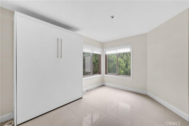 260 Cagney Ln Unit 105, Newport Beach, CA 92663 - unfurnished bedroom featuring baseboards and light tile patterned flooring
