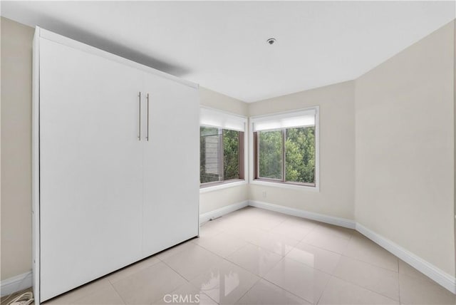 260 Cagney Ln Unit 105, Newport Beach, CA 92663 - unfurnished bedroom featuring baseboards and light tile patterned flooring