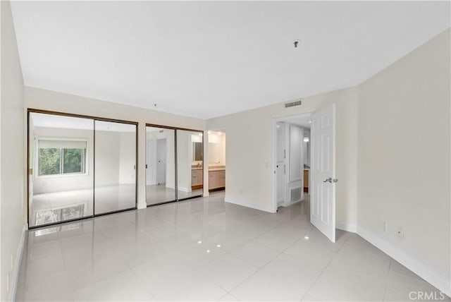 260 Cagney Ln Unit 105, Newport Beach, CA 92663 - unfurnished bedroom with multiple closets, baseboards, and light tile patterned flooring