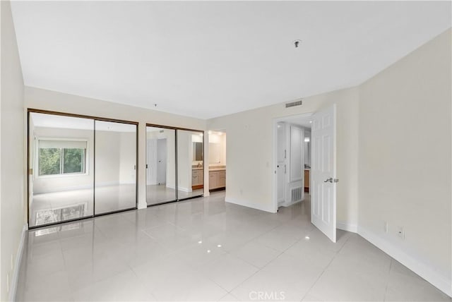 260 Cagney Ln Unit 105, Newport Beach, CA 92663 - unfurnished bedroom with multiple closets and light tile patterned floors