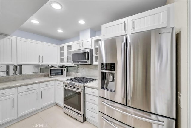 kitchen featuring light stone countertops, light tile patterned floors, appliances with stainless steel finishes, and white cabinetry