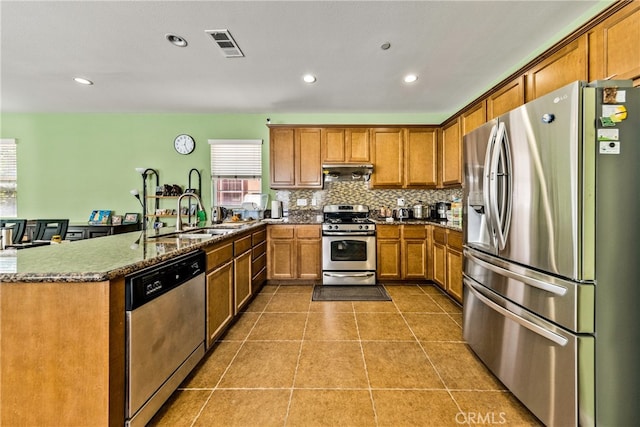 kitchen featuring appliances with stainless steel finishes, backsplash, range hood, sink, and tile patterned floors