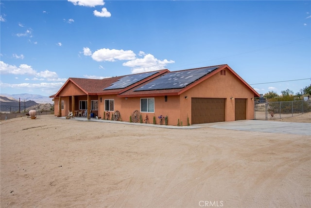 ranch-style house featuring a mountain view, solar panels, and a garage