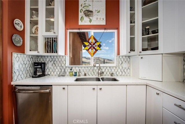 kitchen featuring dishwasher, backsplash, sink, and white cabinetry