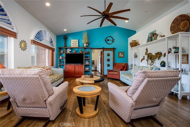 living room featuring ceiling fan, a barn door, hardwood / wood-style floors, and vaulted ceiling