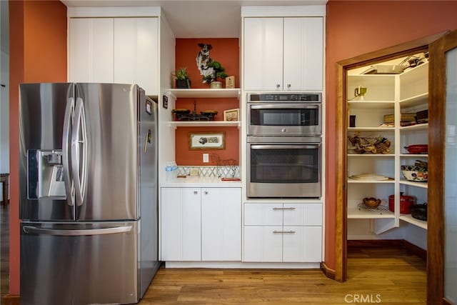 kitchen with light hardwood / wood-style floors, stainless steel appliances, and white cabinets