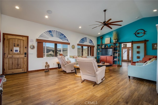 living room featuring a barn door, wood-type flooring, lofted ceiling, and ceiling fan