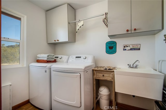 laundry area featuring cabinets, wood-type flooring, washing machine and clothes dryer, and sink