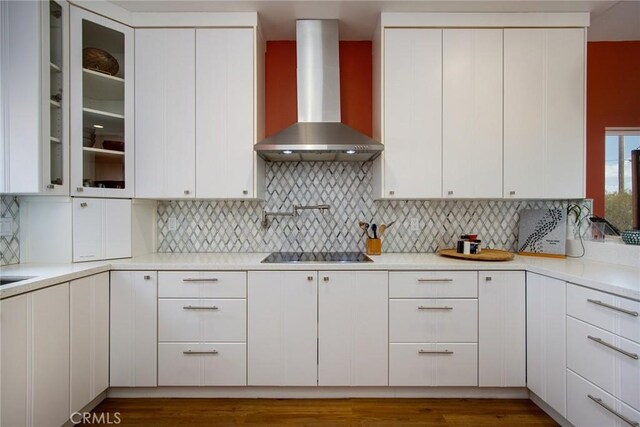 kitchen featuring wall chimney exhaust hood, black electric stovetop, white cabinets, and dark hardwood / wood-style flooring