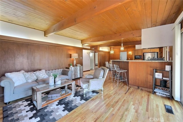 living room with beamed ceiling, light wood-type flooring, wood ceiling, and wood walls