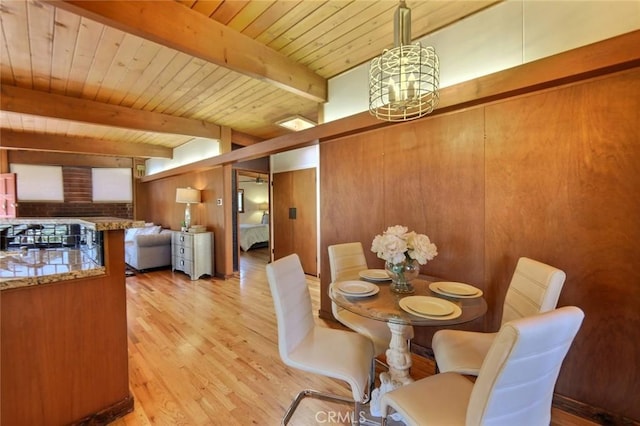 dining room with wood ceiling, wooden walls, beam ceiling, a chandelier, and light hardwood / wood-style floors