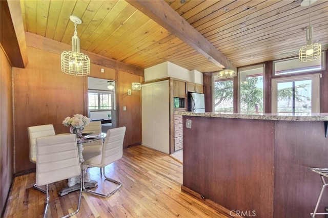 interior space with a wealth of natural light, stainless steel fridge, hanging light fixtures, and light wood-type flooring