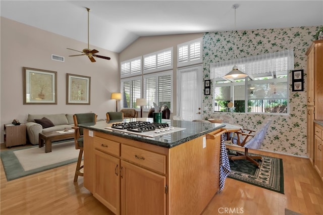 kitchen with white gas cooktop, light hardwood / wood-style floors, a center island, hanging light fixtures, and a kitchen breakfast bar