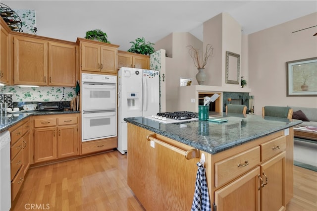 kitchen featuring dark stone counters, light wood-type flooring, white appliances, and tasteful backsplash