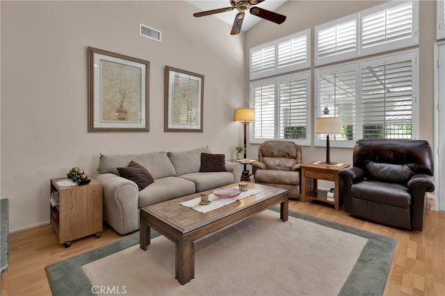 living room with ceiling fan, light hardwood / wood-style flooring, and high vaulted ceiling