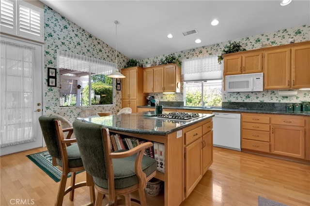 kitchen with a center island, lofted ceiling, hanging light fixtures, light hardwood / wood-style flooring, and white appliances