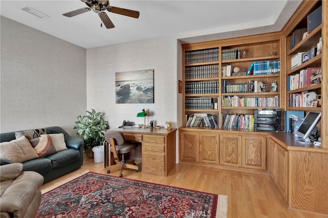 office space featuring built in desk, light hardwood / wood-style floors, and ceiling fan