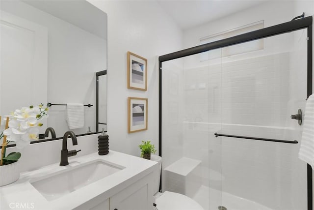 bathroom featuring vanity, toilet, and a shower with door