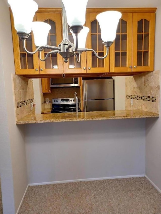 kitchen with light stone counters, kitchen peninsula, backsplash, and stainless steel appliances