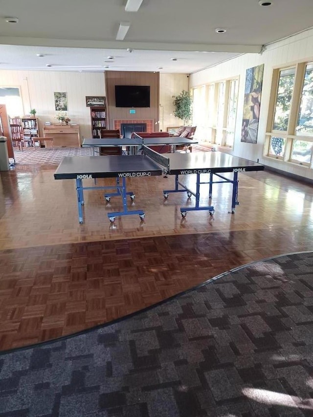 playroom featuring dark parquet flooring and a tile fireplace