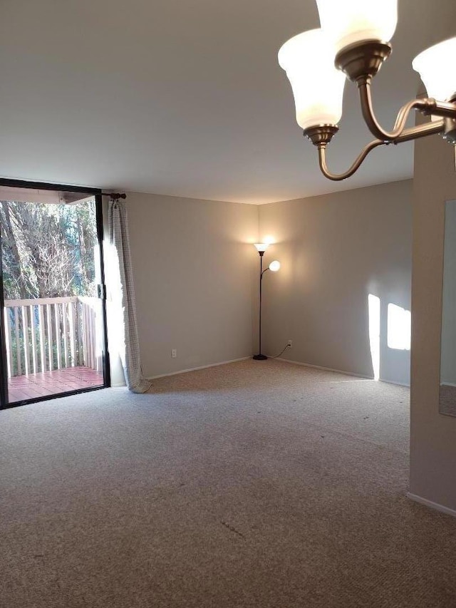 carpeted spare room with an inviting chandelier