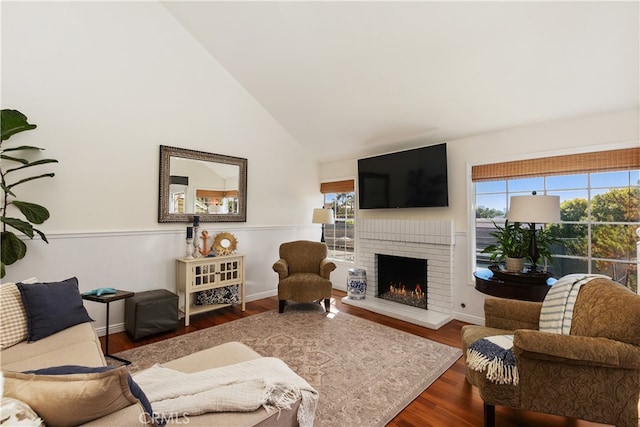 living room with high vaulted ceiling, dark wood-type flooring, and a brick fireplace