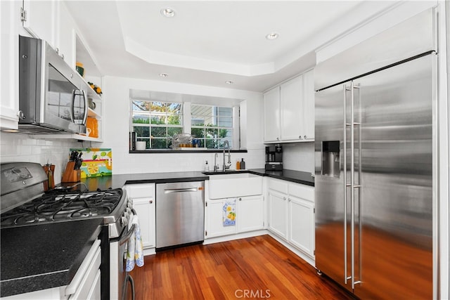 kitchen with white cabinets, sink, tasteful backsplash, appliances with stainless steel finishes, and dark hardwood / wood-style flooring