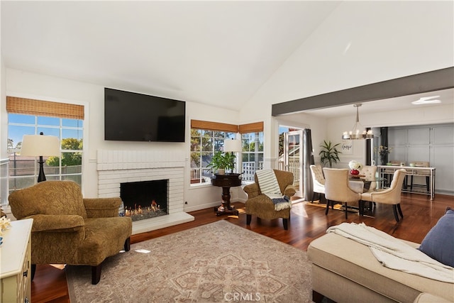 living room featuring a notable chandelier, dark hardwood / wood-style flooring, high vaulted ceiling, and a brick fireplace