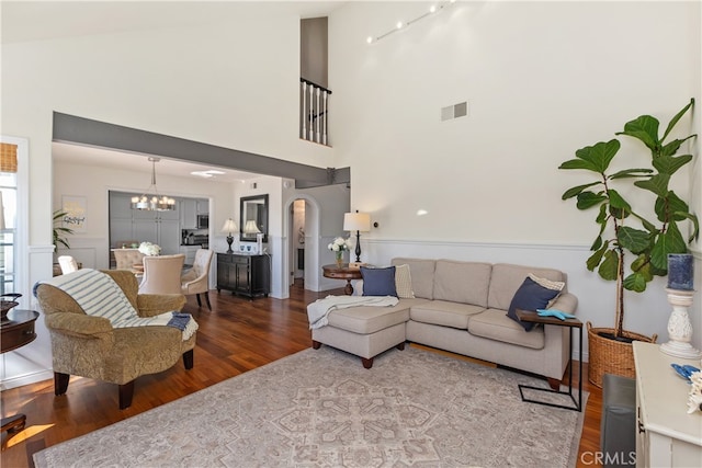 living room featuring high vaulted ceiling, wood-type flooring, and an inviting chandelier