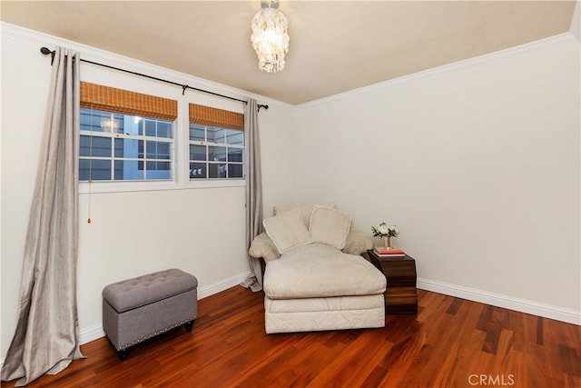 sitting room with ornamental molding and dark wood-type flooring